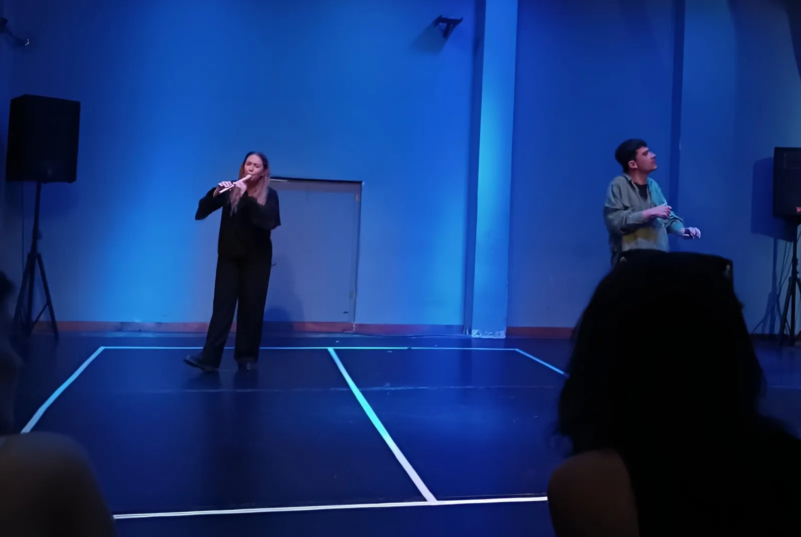 Maria playing the flute on stage in blue light during Cyrano de Bergerac
