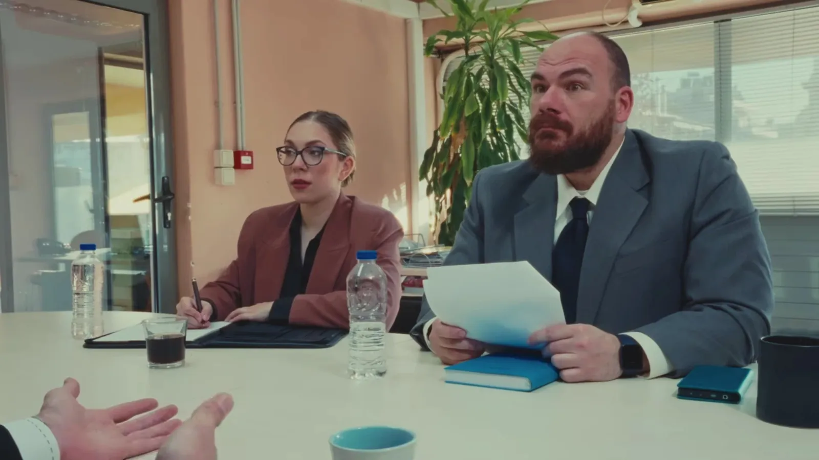Maria as the trainee lawyer at a meeting table in the Nerdula video